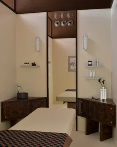 A modern spa or salon with a wooden table and mirror, featuring neatly arranged bottles and a vase, in a clean and organized space