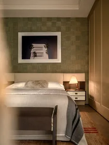 Cozy bedroom with a wooden floor, a modern bed, a table lamp, and a picture on the wall