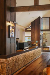 Cozy coffee shop interior with a wooden counter, dining table, and chairs, featuring soft lighting and a warm atmosphere