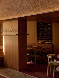 Cozy modern dining space with a long wooden table, wine glasses, and dim lighting