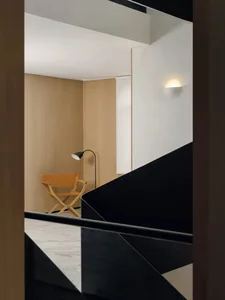 Cozy living room with a wooden floor, a chair, a lamp, and a wooden staircase with a black railing
