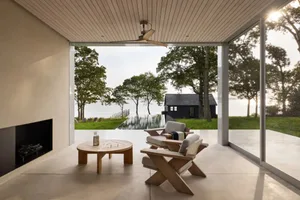 A backyard patio with a round wooden table and chairs, surrounded by natural and artificial materials, with warm sunlight and a relaxed atmosphere