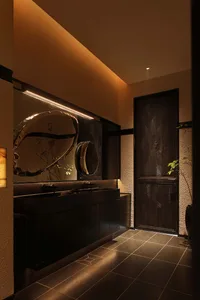 A modern bathroom with a sink and mirror, featuring a dimly lit space with clean lines and minimalistic design