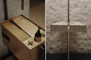 A modern bathroom with a gold sink and stone countertop, set against a stone wall in a dimly lit space