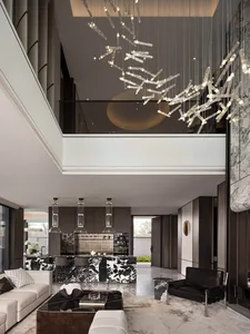Large modern living room with a high ceiling, black and white decor, natural light, and a chandelier