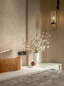 Cozy bedroom with a bed, nightstand, and vase with flowers on a patterned wallpaper background