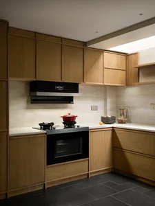 Modern kitchen with wooden cabinets, black oven, and stove top, featuring a sink and a bowl on the counter in a dimly lit space
