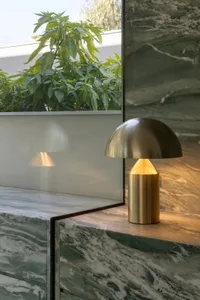 A modern living space with a marble countertop, a gold lamp, and natural light from a large window