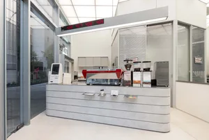 A modern coffee shop with a metal counter, large window, and natural light, creating a welcoming atmosphere