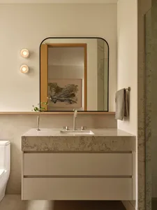 Bathroom with a white color scheme, dim lighting, and a marble sink, mirror, and towel rack