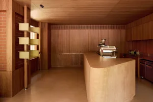 Warm and inviting kitchen with wooden floors and walls, featuring a counter with a coffee maker and a sink, lit by natural light