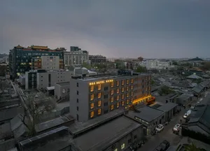 一座城市夜晚的街道，酒店和亮著的招牌，周圍是其他建築物和汽車