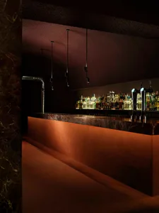 A well-lit bar with a marble countertop, bottles of various sizes arranged in a visually appealing manner, and an inviting atmosphere