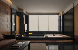 現代浴室內有黑色浴缸、窗戶和鏡子，具有清潔簡約設計、自然光線和深度的感覺