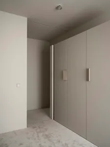 A dimly lit gray hallway with concrete walls and white surfaces, featuring a doorway
