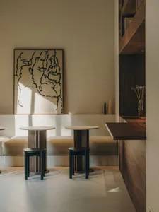 A modern living room with a large painting, two couches, a dining table, and several chairs, set in a well-lit space with a contemporary style