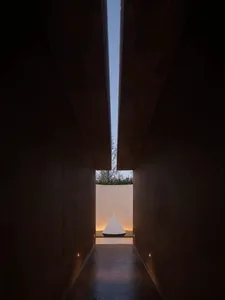 A dark room with a small white triangle on the floor, creating a focal point in the space