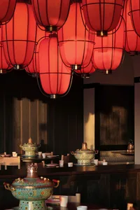A modern restaurant dining area with a long wooden table and chairs, surrounded by ceramic bowls and cups, in a warm and inviting atmosphere