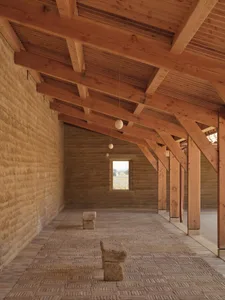 A dimly lit, cozy space with a stone floor, stone walls, and a wooden ceiling, creating a warm and inviting atmosphere