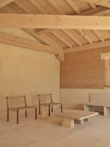 Dining area with a stone wall, wooden floor, and natural light, featuring a stone bench and table, and a dining table with chairs