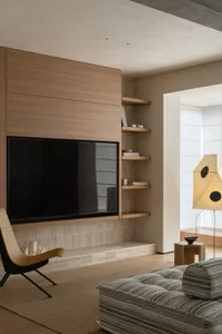Comfortable living space with a couch, chair, and bookshelf, featuring a mix of natural and artificial lighting, wood, and glass materials