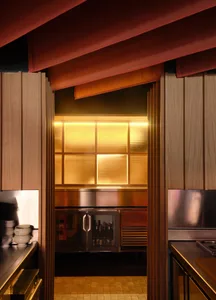 A dimly lit kitchen with a counter and refrigerator, featuring a few bottles on the counter