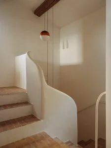 A modern staircase with a white wall and concrete floor, surrounded by a minimalist atmosphere with natural light