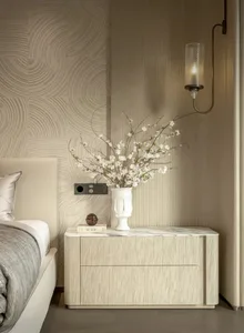 Cozy modern bedroom with a bed, dresser, and vase with flowers, featuring soft warm lighting and a focus on simplicity and functionality