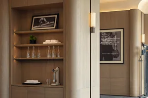 Cozy room with wooden walls and floors, featuring a wooden cabinet with a mirror and a picture, bottles, and a potted plant, in a dimly lit space with a mix of modern and traditional elements