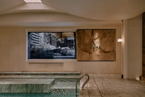 Bathroom with a large window, a pool, and a stone wall, featuring modern design and natural light