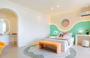 Cozy bedroom with a bed, bench, and chair, featuring a green and white color scheme and wooden accents