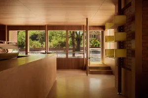 A warm and inviting space with a wooden floor, a counter, a dining table, and chairs, lit by natural light from the windows