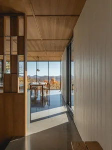 Wooden kitchen with a dining table and chairs, adjacent to a dining area with a large window allowing natural light