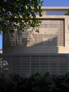 Photograph of a concrete building with a grid pattern on the wall and a window on the side, set against a natural outdoor backdrop