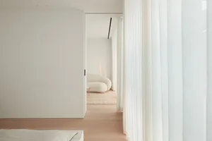 A modern living room with a white color scheme, natural light, and comfortable seating options
