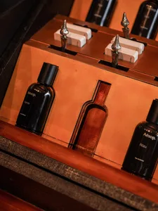 A display case with various bottles and vases arranged in it, set against a brown wooden background