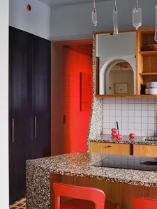 A modern kitchen with a marble countertop, a black stove, and various items such as apples and bowls, set against a bright and well-lit background
