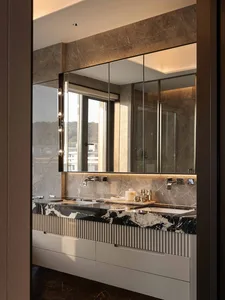 Bathroom with a marble countertop and a large mirror above it, in a dimly lit modern space