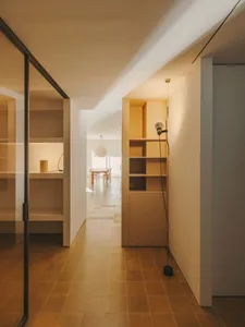 Cozy living room with a wooden floor, tile floor in the hallway, and a dining table and chairs, lit by dim warm lighting