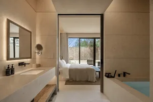 A modern minimalist bedroom with a bed, sink, and door, featuring predominantly white surfaces and a clean appearance