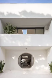 A bright and inviting living room with a modern house featuring a circular window and a potted plant, well-lit with a warm atmosphere