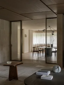 一間充滿自然光線的客廳，擺放著餐桌、椅子和一大窗戶，周圍是木材和玻璃元素