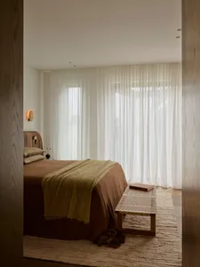 Cozy bedroom with a brown-covered bed, a bench, and natural light from a window