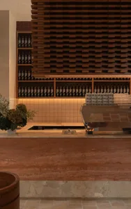A casual kitchen counter with a wooden surface, featuring a coffee maker and various bottles in a inviting arrangement