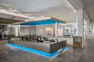 A modern coffee shop with a large blue metal canopy, a clean and inviting interior, and a focus on providing a pleasant experience for visitors