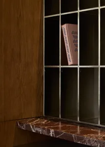 一間舒適的生活空間內有木櫃、鐵架書櫃和粉紅盒子，在周圍有書籍和溫暖的氣氛