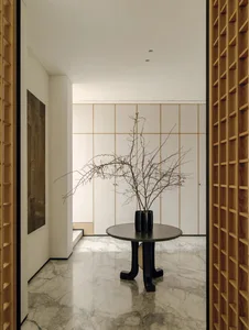 A modern dining space with a black table, white walls, and a potted plant, flooded with natural light from a large window