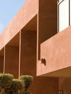 Photograph of a building with a red brick exterior, featuring a large window and two smaller windows, showcasing its architectural details and materials