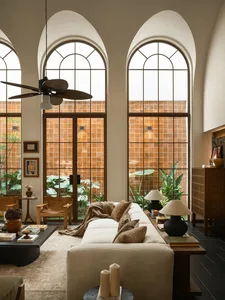 A bright and welcoming living room with a white couch, chair, and decorative items, filled with natural light and a potted plant, creating a comfortable and inviting space