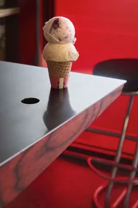 A red table with a white cupcake on top, set against a plain background